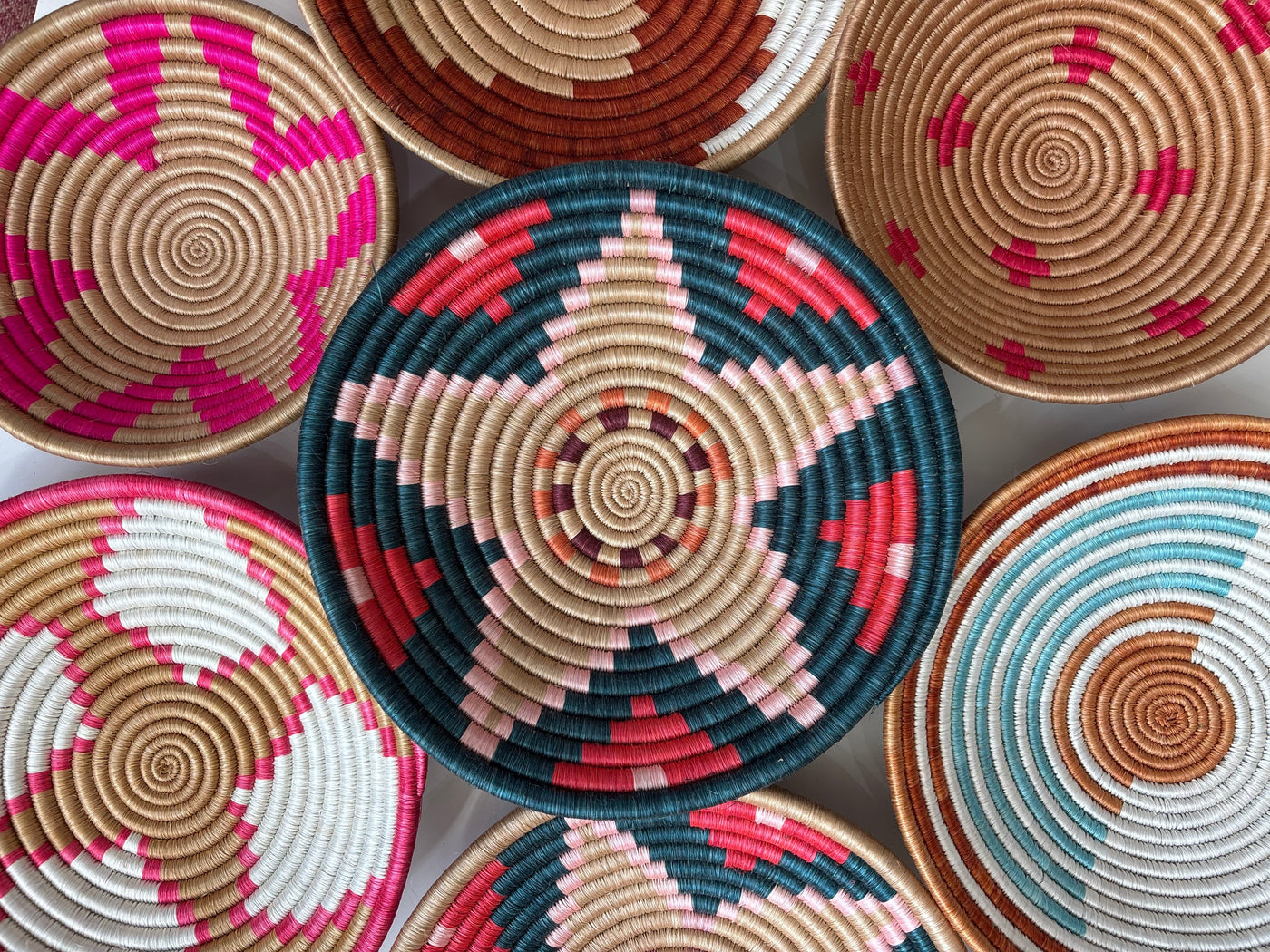 Collection of colorful woven baskets with circular patterns on a light gray background